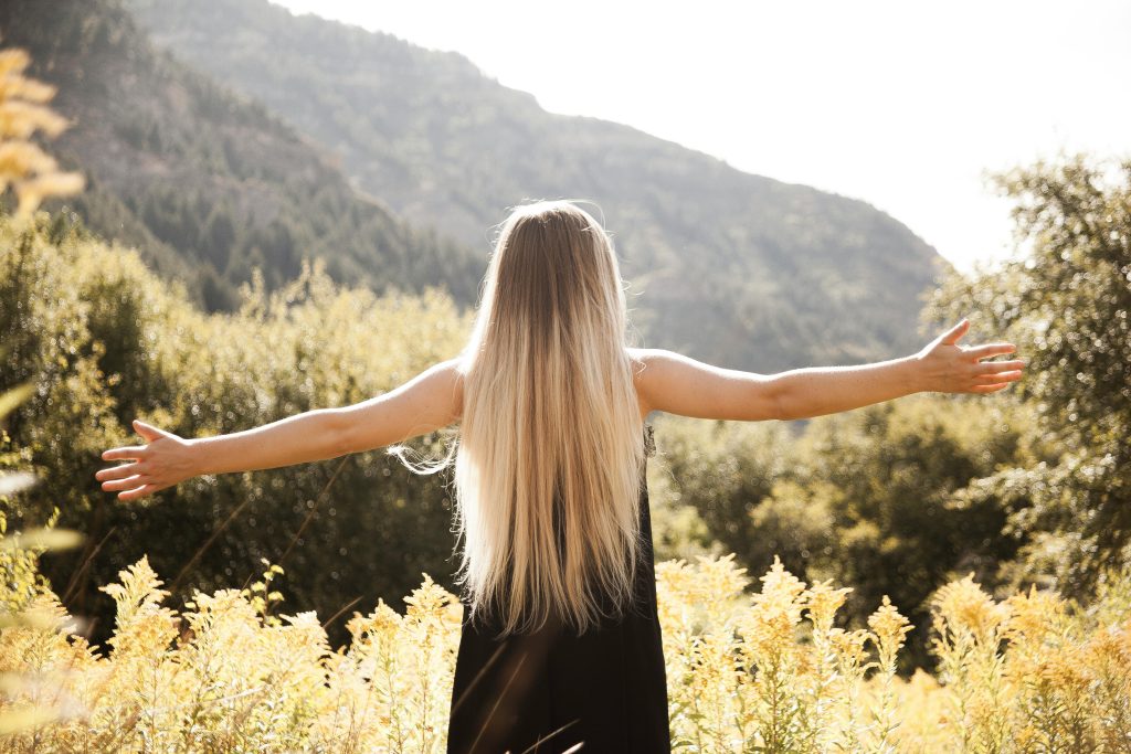Young woman with arms open, enjoying freedom in a mountainous landscape.